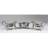 A pair of Edward VII silver oval sauce boats with shaped rims and moulded scroll handles, on three