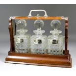 A 20th Century oak and plated mounted three bottle tantalus with handled curved top section with