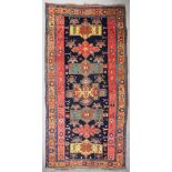 An antique Karabagh carpet woven in muted colours with seven geometric medallions on a dark blue