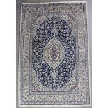 A Nain Carpet woven in blue, red and tan with oval double headed medallion, conforming spandrels and