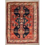 A Karachopf Caucasian carpet woven in colours with three medallions and filler motifs on a madder