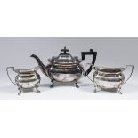 A George V silver rectangular three piece tea service with shaped rims, angular handles and on