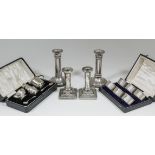 A pair of Edward VII silver pillar candlesticks with circular sconces, embossed throughout with