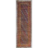 An antique Caucasian runner woven in colours with endless boteh repeats on a dark blue ground within