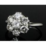 A 1960s silvery coloured metal mounted diamond set flowerhead pattern ring, the central brilliant