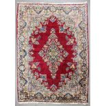 An early 20th Century Kirman carpet, woven in colours with floral lozenge medallion and conforming