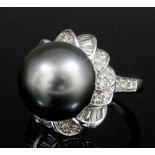 A modern 18ct white gold, black pearl and diamond set ring, the 12mm black pearl within scrolling