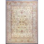 A modern Persian style carpet, woven in muted colours with all over floral motifs on a pale fawn