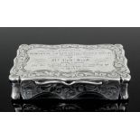 A Victorian silver presentation snuff box of rectangular form with shaped and incurved sides, the