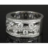 A modern 18ct white gold all diamond set ring, the scrolling open work face pave set with twenty-