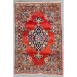 A Mahal rug woven in colours with a bold floral filled central medallion, on a madder ground with