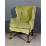 A wing back easy chair of Georgian design, upholstered in green velour, on shell capped cabriole