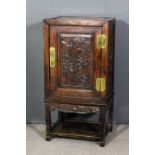 A Chinese rosewood panelled dwarf cupboard, enclosed by single door carved with dragons and mythical