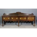 An old oak low dresser base with shaped upstande, fitted four frieze drawers with cross banded