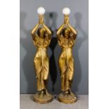A pair of painted fibreglass electric standard lamps in the form of Egyptian women holding aloft a