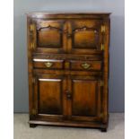 A panelled oak cupboard in the manner of Titchmarsh & Goodwin, the upper part enclosed by a pair