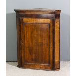 A late Georgian oak and mahogany banded hanging corner cupboard with moulded cornice, fitted two