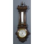 A late Victorian oak cased aneroid barometer and thermometer, the 8ins diameter silvered dial with