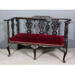 A late Victorian dark oak framed settee, the whole carved with birds, trailing floral scroll