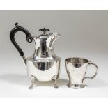 An Edward VII plain silver oval hot water jug with wavy rim, ebonised handle and on four paw feet,