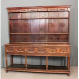 An 18th Century oak dresser, later applied with beaded mouldings, the upper part fitted two shelves,