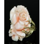 A modern 14k gold coral mounted ring, the oval pale pink coral face carved in high relief with a