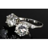 A silvery coloured metal mounted two stone crossover ring, set with two brilliant cut diamonds, each