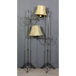 A pair of oxidised metal electric standard lamps, with cross pattern finials, scroll brackets