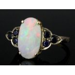 A 1960s gold coloured metal mounted opal and sapphire ring, the oval cut opal approximately 3ct