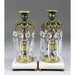 A pair of late 19th/early 20th Century gilt brass lustre candlesticks hung with cut prismatic drops,