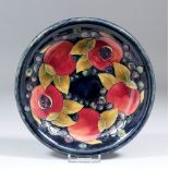 A Moorcroft pottery plate, tube lined with "Pomegranate" design on a deep mottled blue ground, 8.