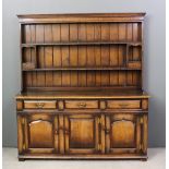 A panelled oak dresser in the manner of Titchmarsh & Goodwin, the upper part with moulded cornice,