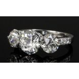 A modern silvery coloured metal mounted three stone diamond ring, the central brilliant cut stone