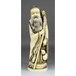 A Chinese carved ivory tusk figure of a standing Sage holding a staff and flask, 16ins (407mm)