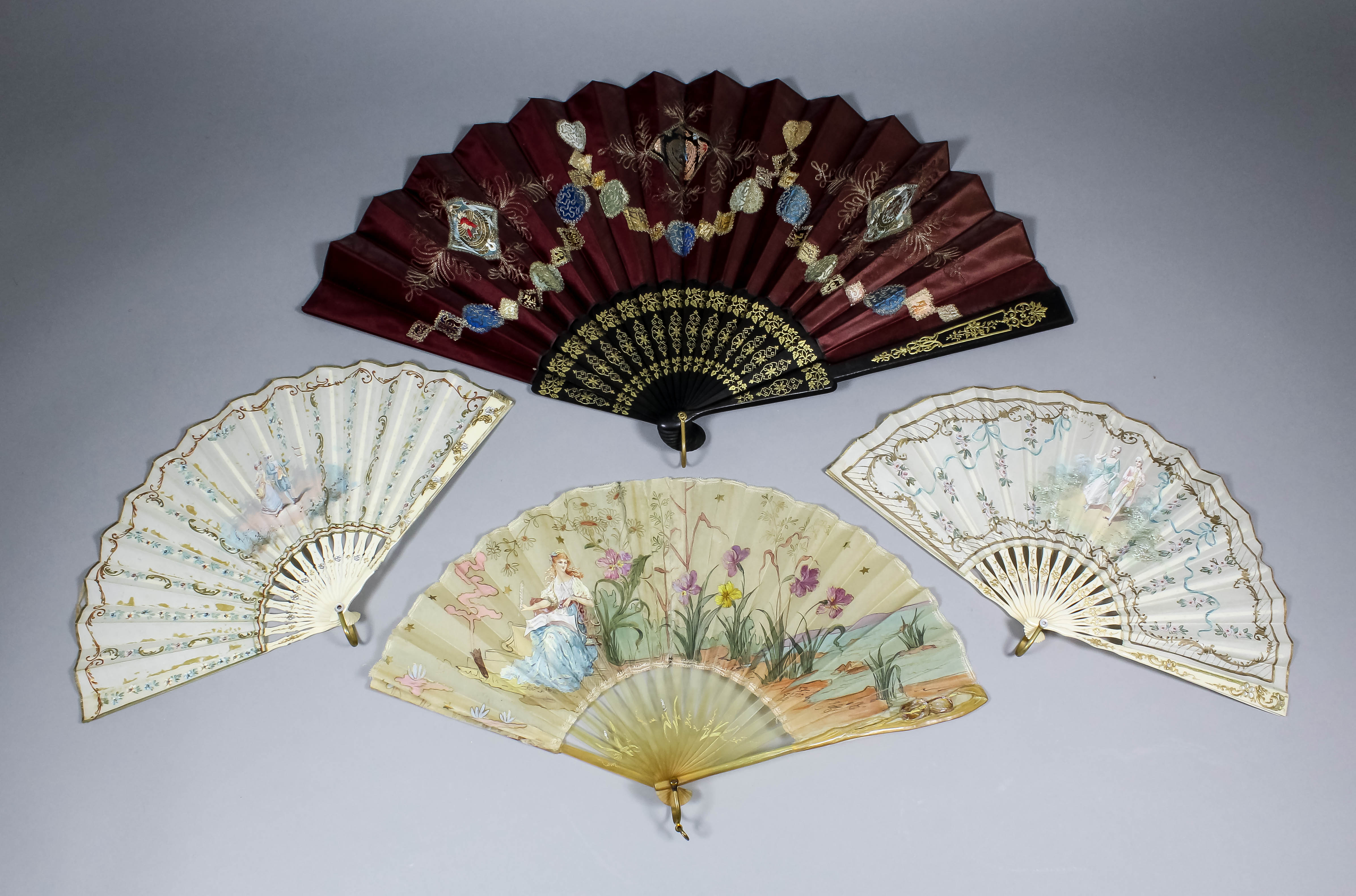 A French horn and silk fan, the silk panel painted with a seated muse making music within a