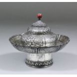 A Tibetan silvery metal censer, chased with Buddhist designs and surmounted with a red coral knop,