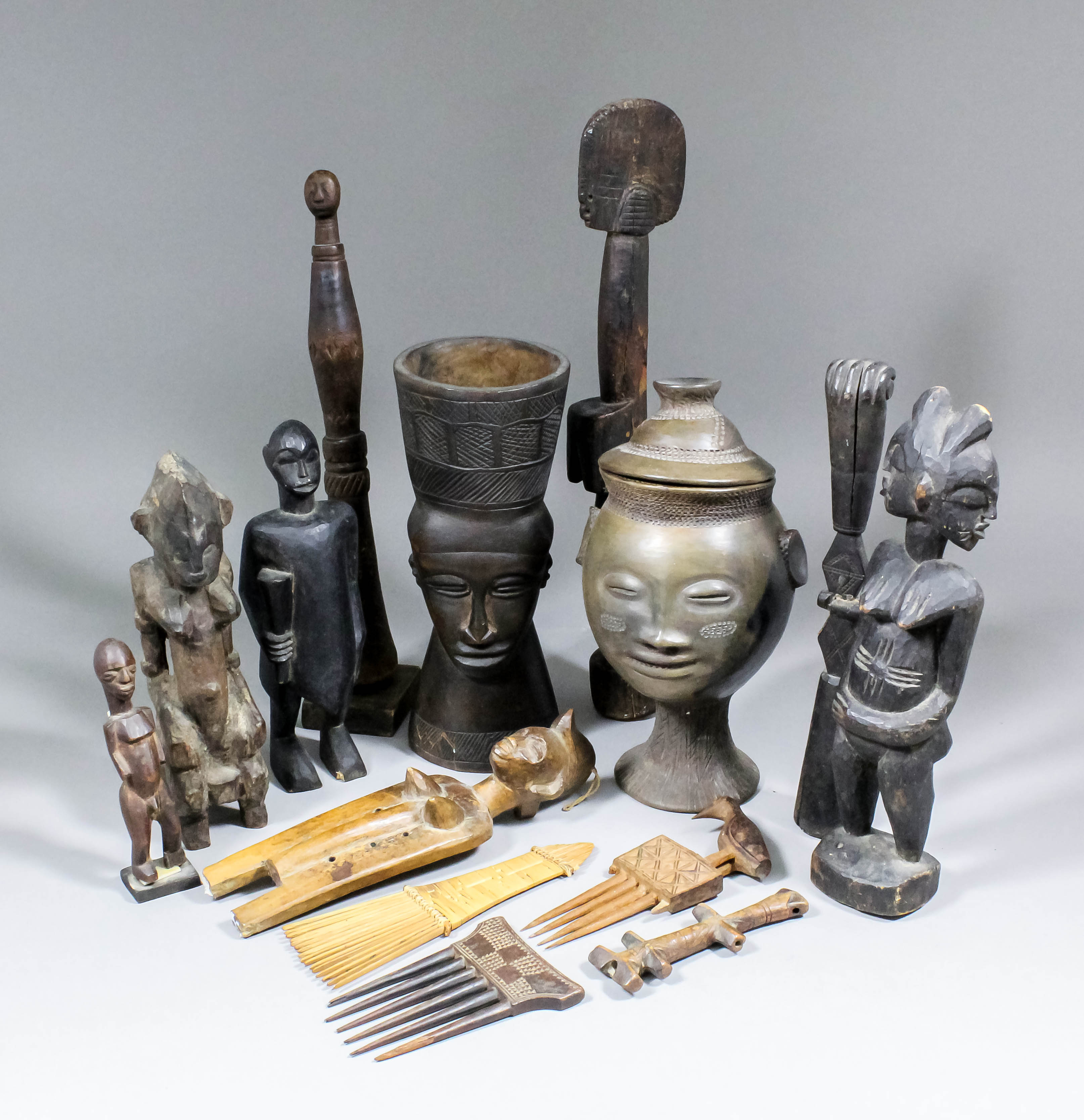 An interesting collection of West African carved wooden objects, including - Handled mortar carved