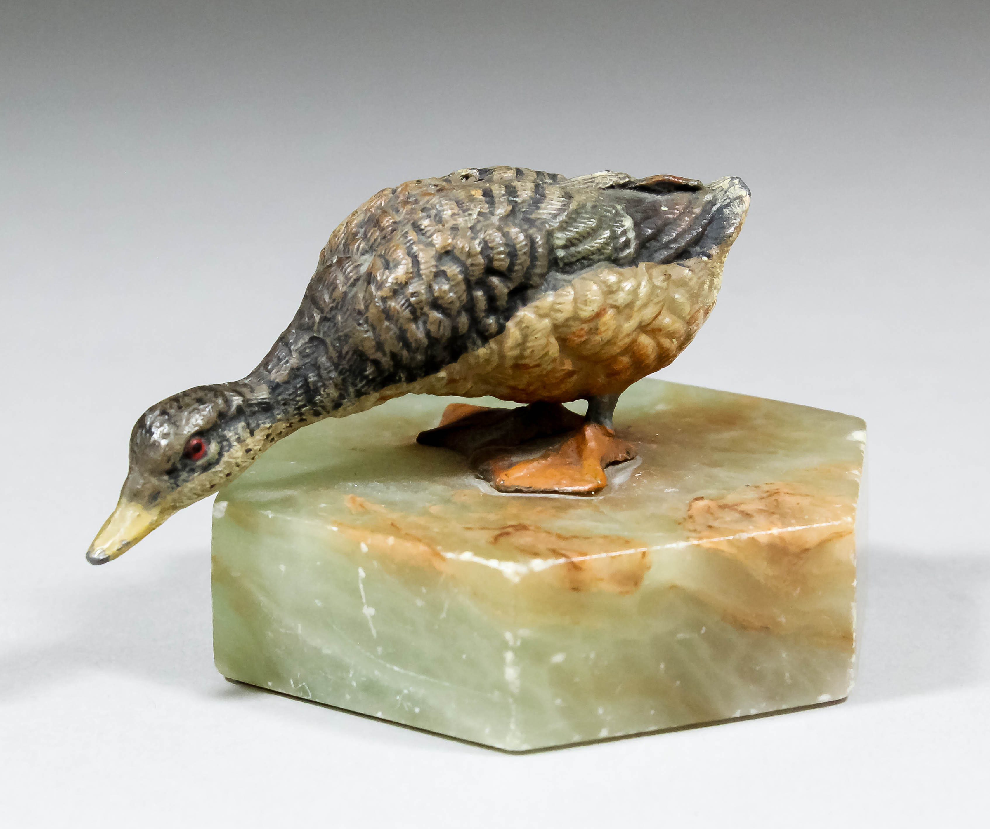 An early 20th Century cold painted metal figure of a goose mounted on an hexagonal onyx base, 2ins