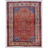 A Sarouk rug woven in colours with three rows of bold geometric motifs on a terracotta ground and