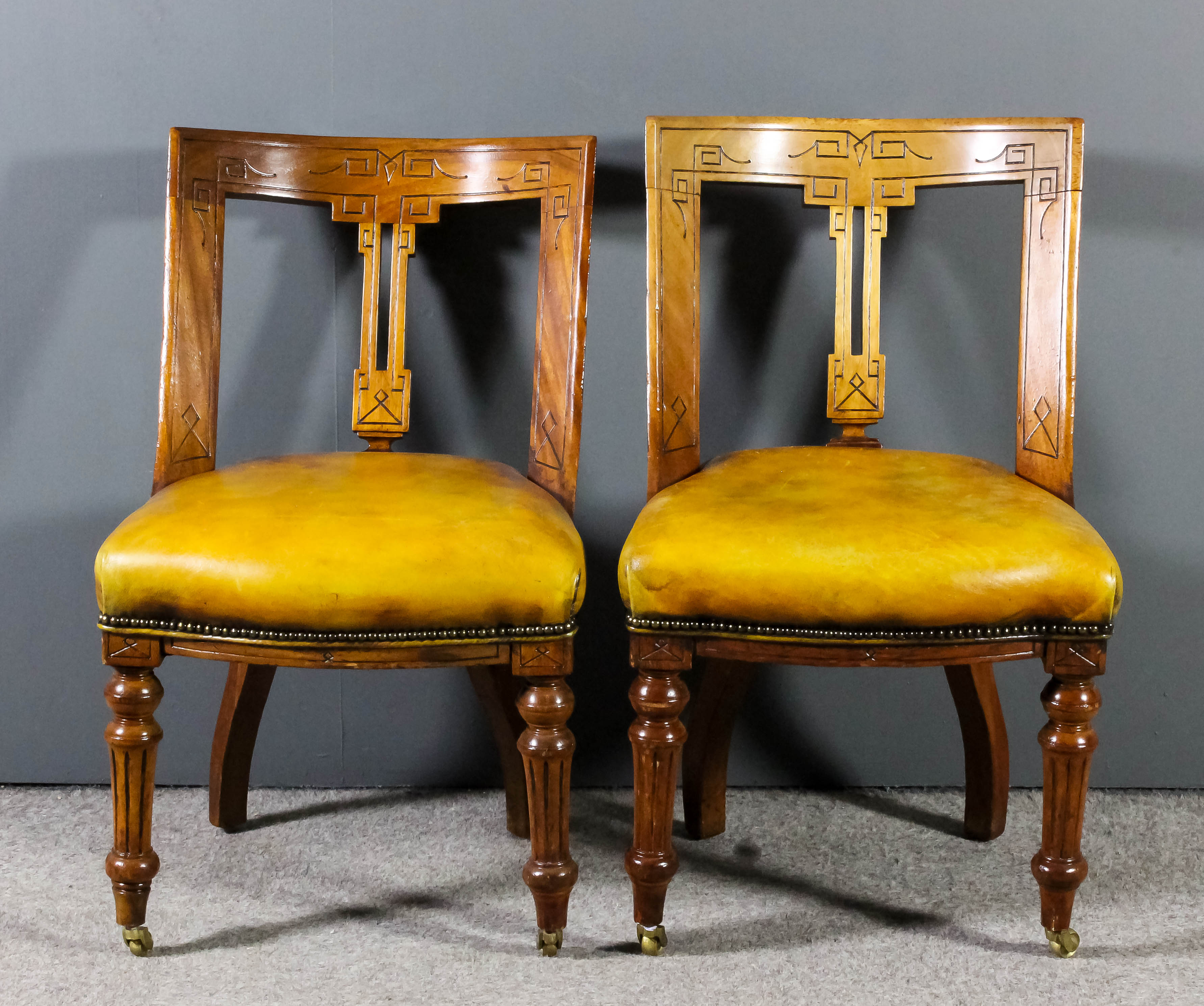 A pair of Victorian mahogany framed dining chairs, the curved crest rails, uprights and fretted