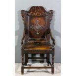A late 17th Century panelled oak armchair with shaped crest rail carved with the initials "HS" and