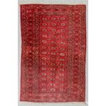 A Turkman rug woven in dark brown rose and ivory with three rows each of fourteen small octagonal