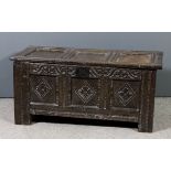 A 17th Century panelled oak coffer with three fielded panel lid, the front carved with leaf scroll