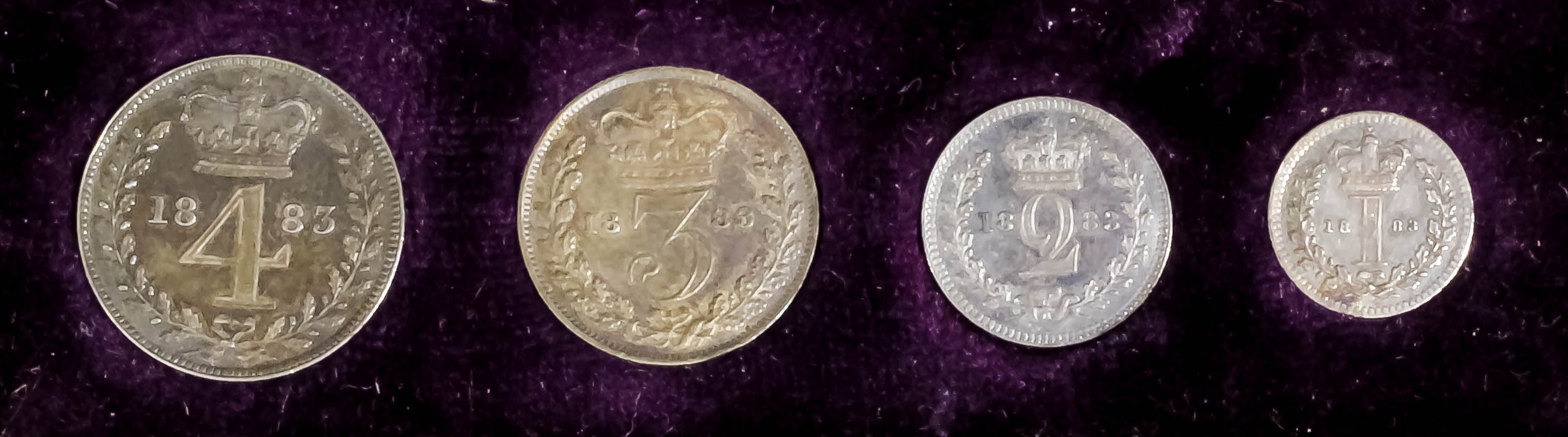 A set of four Victoria 1883 Maundy Coins (E.F./ uncirculated with toning) in dark red leather