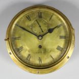 A polished brass cased ship's bulkhead timepiece, the 8ins diameter brass dial with Roman