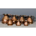 A Harlequin set of eleven graduated Victorian copper jug measures, from 4 gallons, 14.5ins high to 1