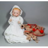 An Armand Marseille 341/3.K. "Baby" doll with closing blue eyes, wearing linen gown and cap, and