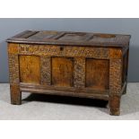 A 17th Century panelled oak coffer with three panel lid and front, the front carved with entwined