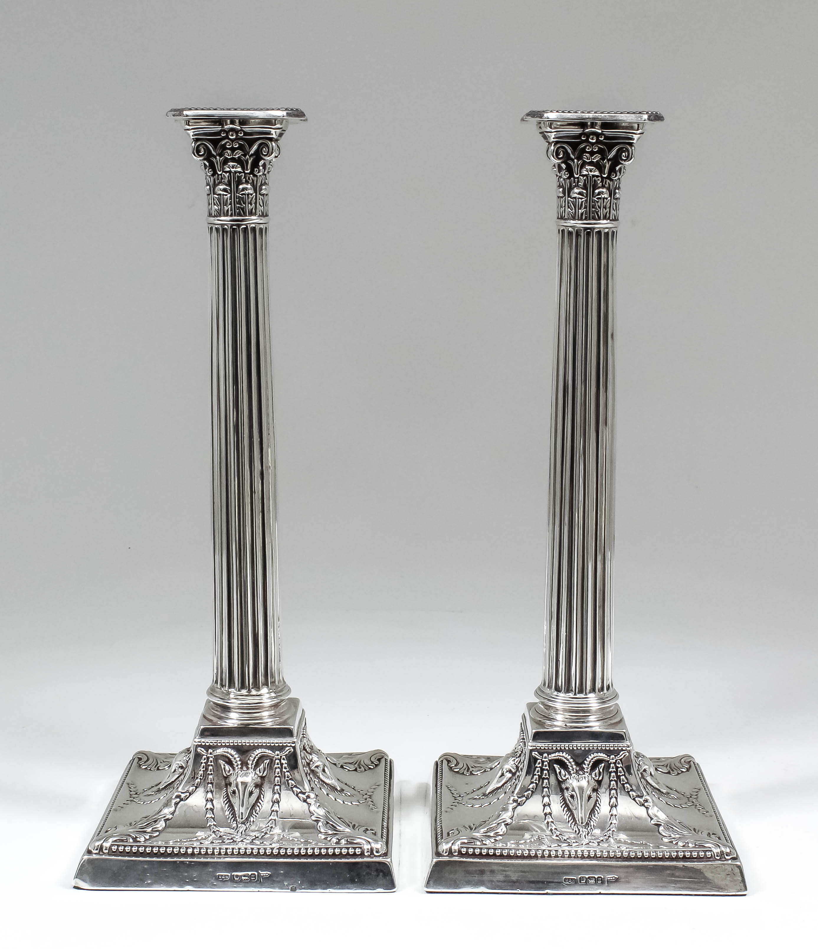 A pair of late Victorian silver pillar candlesticks with cast Corinthian capitols and fluted