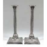 A pair of late Victorian silver pillar candlesticks with cast Corinthian capitols and fluted